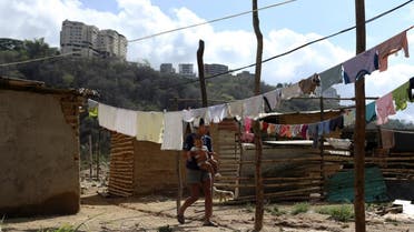 A woman walks across hanged clothes on a vacant lot where families are settling since they cannot afford to pay rent anymore, in the municipality of Sucre, near Caracas, Venezuela, on June 12, 2020. (Reuters)