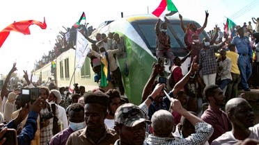 Sudanese protesters cheer as they greet fellow demonstrators upon their arrival on a train from Madani, the capital of Sudan's east-central al-Jazirah state, to join a rally in support of a civilian-led transition to democracy, on September 30, 2021. (AFP)