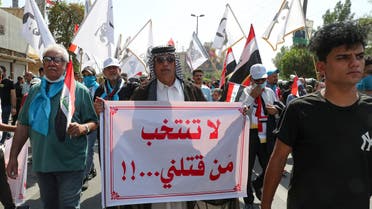 Iraqis hold placards as they rally at Fardous square in central Baghdad, on October 1, 2021, demanding justice for demonstrators killed during the October 2020 anti-government protests, ahead of the October 10 parliamentary elections. The writing in Arabic reads:  Don't vote for those who killed us. (AFP)