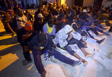 مهاجرون يجلسون على الأرض في مركز احتجاز في تاجوراء الليبية