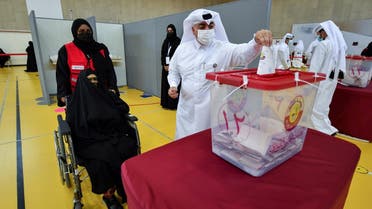 A man casts a ballot as a woman in a wheelchair looks on during the Gulf Arab state's first legislative elections for two-thirds of the advisory Shura Council, in Doha, Qatar October 2, 2021. (Reuters)