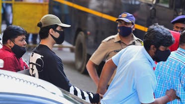 Bollywood actor Shah Rukh Khan's son Aryan Khan (2L) is being escorted by law enforcement officials outside the Narcotics Control Bureau (NCB) office after he was allegedly brought in for questioning along with others following a raid at a party on a cruise ship, in Mumbai on October 3, 2021. (AFP)