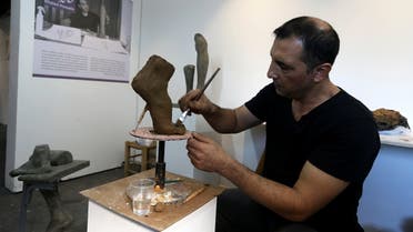 Palestinian artist Khaled Hussein works on a sculpture resembling an amputated foot in his workshop to bring attention to the plight of amputees in Gaza City, September 28, 2021. (Reuters/Ibraheem Abu Mustafa)