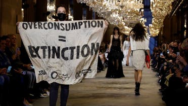 An activist walks on the ramp with a banner that says “Overconsumption = Extinction” as she crashes the designer Nicolas Ghesquiere Spring/Summer 2022 women's ready-to-wear collection show for fashion house Louis Vuitton during Paris Fashion Week in Paris, France, on October 5, 2021. (Reuters)