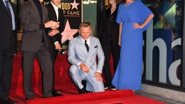 British actor Daniel Craig (C) kneels to look at his newly unveiled star, flanked by (from R) Chamber of Commerce Chair Nicole Mihalka, US producer Barbara Broccoli, US actor Rami Malek, Los Angeles City Councilmember Mitch O'Farrell and US screenwriter Michael G. Wilson during the ceremony to honor him with a star on the Hollywood Walk of Fame in Los Angeles, California, on October 6, 2021. (AFP)