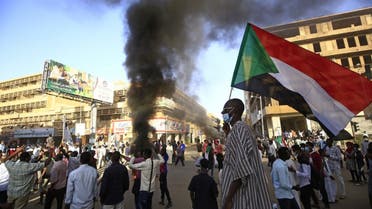 A Sudanese man wearing a face mask waves his country's national flag during protests in the capital Khartoum to mark the second anniversary of the start of a revolt that toppled the previous government, on December 19, 2020. (AFP)
