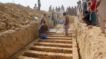 Afghan men dig graves during a mass funeral after the previous day's suicide bomb blast inside a mosque in Kunduz, Afghanistan October 9, 2021. (Reuters)