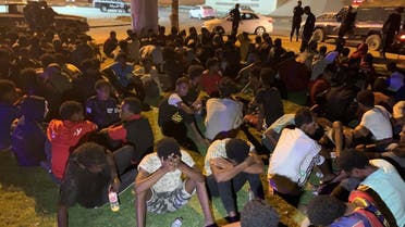 Migrants sit after they were detained by Libyan security forces in Tripoli, Libya, on October 8, 2021. (Reuters)