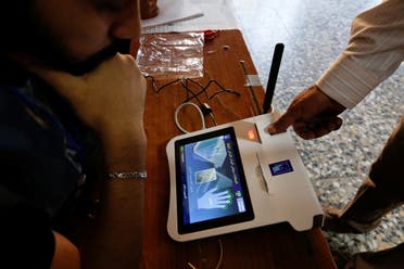 The finger of an Iraqi election official opens a device to start the legislative elections in Iraq, in Sadr City, Baghdad, October 10, 2021. (Reuters)