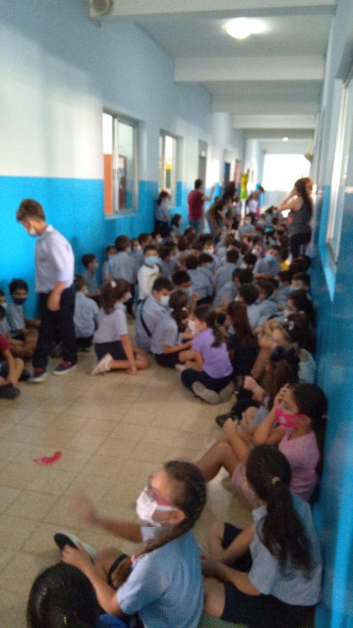 Students huddle in a school hallway to avoid the gunfire in Beirut. (Twitter)
