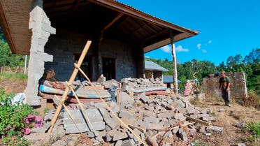 A man stands near his house damaged by an earthquake in Karangasem on the island of Bali, Indonesia, Saturday, Oct. 16, 2021. A few people were killed and another several were injured when a moderately strong earthquake and an aftershock hit the island early Saturday. (AP Photo/Andi Husein)