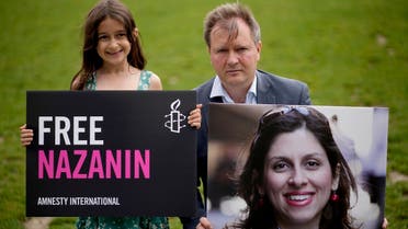 Richard Ratcliffe, the husband of imprisoned British-Iranian Nazanin Zaghari-Ratcliffe and their seven year old daughter Gabriella pose for the media in Parliament Square, London, to mark the 2,000 days she has been detained in Iran, on Sept. 23, 2021. (AP)