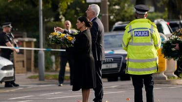 British Home Secretary Priti Patel (left), reads the note on a bouquet of flowers while standing with Speaker of the House of Commons Lindsay Lindsey Hoyle as they arrive at the scene where a member of Parliament was stabbed on Friday, in Leigh-on-Sea, Essex, England, on Oct. 16, 2021. (AP)