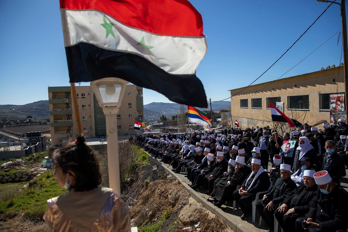 In this Feb. 14, 2021 file photo, Druse supporters of Syrian President Bashar Assad wave Syrian flags during a rally close to the border demanding the return of the Golan Heights, captured by Israel in 1967, in Majdal Shams, Golan Heights. (AP)