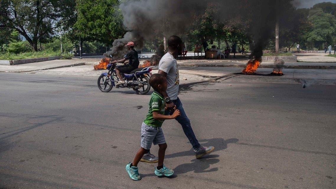 A man and a child walk by burning tires on a street in Port-au-Prince, Haiti, on Oct. 17, 2021. (AP)