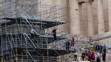 Protesters shout slogans as they climb on scaffolding at the Acropolis hill, in Athens, Greece, Sunday, Oct. 17, 2021. (AP)