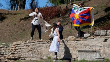 Police officers run to detain protesters displaying a Tibetan flag and a banner disrupting the lighting of the Olympic flame at Ancient Olympia site, birthplace of the ancient Olympics in southwestern Greece, Oct. 18, 2021. (AP)