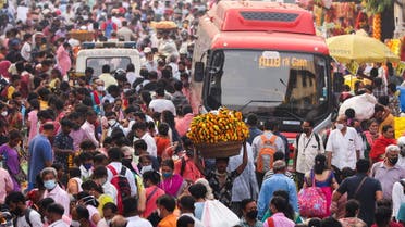 A man carrying flower garlands walks through a crowded market ahead of the religious festival of Dussehra, amidst the spread of the coronavirus disease (COVID-19) in Mumbai, India, October 14, 2021. (Reuters)