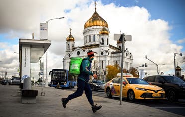 A food delivery courier wearing a protective mask runs in front of Christ the Saviour cathedral, the main Russian Orthodox church in central Moscow, on October 18, 2021, amid the outbreak of Covid-19, caused by the novel coronavirus. (File photo: AFP)