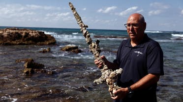 Yaakov Sharvit of the IAA holds a sword believed to have belonged to a Crusader who sailed to the Holy Land almost a millennium ago after it was recovered from the Mediterranean seabed by an amateur diver, the Israel Antiquities Authority said, Caesarea, Israel October 18, 2021. (Reuters)
