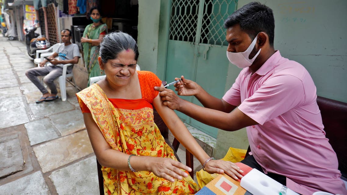 A woman reacts as she receives a dose of the COVISHIELD vaccine, a coronavirus disease (COVID-19) vaccine manufactured by Serum Institute of India, in an alley at a slum area in Ahmedabad, India, September 28, 2021. (Reuters)