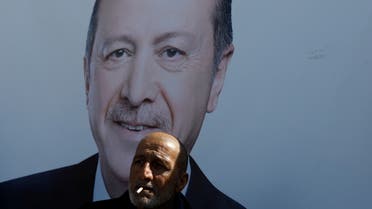A man smokes in front of a portrait of Turkish President Tayyip Erdogan in Istanbul, Turkey, March 28, 2019. REUTERS/Umit Bektas