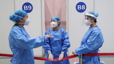 Staff members talk outside booths where people receive a vaccine against the coronavirus disease (COVID-19) at a vaccination center, during a government-organized visit, in Beijing, China, April 15, 2021. (Reuters)
