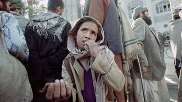 A young Afghan girl begs for some change on November 13, 1996 in front of a mosque in the war-torn Kabul in order to collect enough money to buy food. (File photo: AFP)