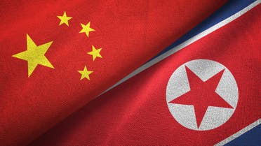 North Korea and China two flags together textile cloth, fabric texture stock photo