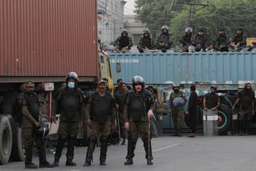 Police officers stand guard to block the road during a protest rally by the banned political party Tehrik-e-Labaik Pakistan (TLP) demanding the release of their leader and the expulsion of the French ambassador over cartoons depicting the Prophet Mohammed, in Lahore, Pakistan, on October 22, 2021. (Reuters)