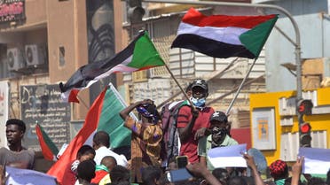 Sudanese demonstrators raise national flags as they take part in a protest in the city of Khartoum Bahri, the northern twin city of the capital, to demand the government's transition to civilian rule, on October 21, 2021. (AFP)