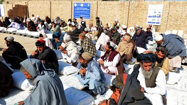 Afghan people sit besides sacks of food grains distributed as an aid by the World Food Programme (WFP) in Kandahar on October 19, 2021. (AFP)