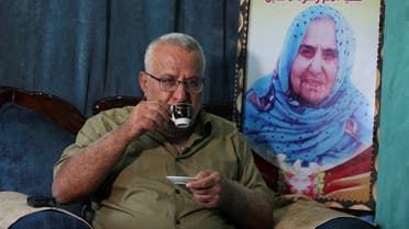 Palestinian Munir Hamo drinks coffee next to his mother's portrait, inside his family house, as he would soon be able to unite with his wife and six children for the first time in 14 years after Israel approved his request for family unification that would finally allow him to travel outside the enclave, in the central Gaza Strip, on October 19, 2021. (Reuters)