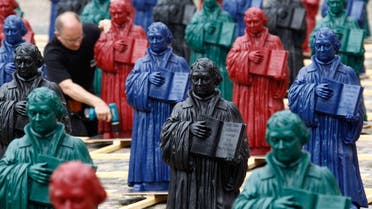 An assistant fixes a plastic statuette of 16th-century Protestant reformer Martin Luther, which is part of the art installation 'Martin Luther - I'm standing here' by German artist Ottmar Hoerl, in the main square in Wittenberg, eastern Germany August 11, 2010. (Reuters)