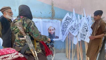 عناصر طالبان أمام صورة لزعيم الحركة هبة الله آخوند زاده
