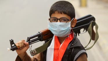 A boy wearing a surgical mask holds a weapon in Sanaa April 3, 2015. Yemen's Meteorological Authority on Friday warned of low visibility due to a sandstorm over parts of the middle east, affecting northern and eastern regions of Yemen. REUTERS/Mohamed al-Sayaghi
