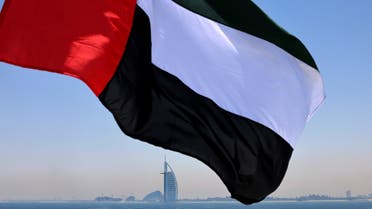 This picture taken on June 3, 2021 shows an Emirati flag fluttering above Dubai's marina with the Burj Al Arab landmark hotel (C) in the background. (AFP)