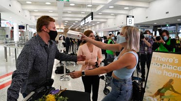 A couple is reunited at Sydney Airport in the wake of coronavirus disease (COVID-19) border restrictions easing, in Sydney, Australia, November 1, 2021. (Reuters)