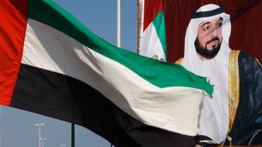 A United Arab Emirates flag waves in front of a big poster of President Sheikh Khalifa bin Zayed al-Nahyan in Abu Dhabi December 15,2009. (Reuters)