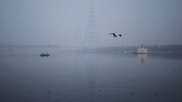 People ride a boat across Yamuna river on a smoggy morning in New Delhi, India, November 4, 2021. (Reuters)