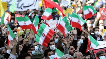 Iranians raise national flags during a rally outside the former US embassy in the capital Tehran on November 4, 2021, to mark the 42th anniversary of the start of the Iran hostage crisis. (AFP)