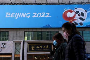 People walk past a banner with a sign of Beijing 2022 Winter Olympic Games, 100 days ahead of the opening of the event, in Beijing, China October 27, 2021. (Reuters/Tingshu Wang)