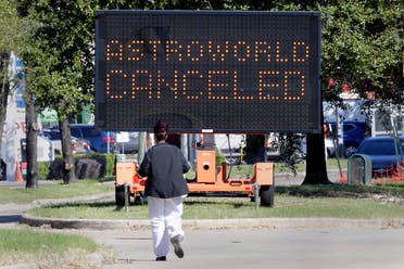  A pedestrian cross Main Street in front of a sign announcing the cancellation of Astroworld on Saturday, Nov. 6, 2021, in Houston. Several people died and numerous others were injured in what officials described as a surge of the crowd at the music festival while Travis Scott was performing Friday night. (AP Photo/Michael Wyke)