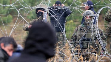 Polish border guards stand near the barbed wire as migrants from the Middle East and elsewhere gather at the Belarus-Poland border near Grodno, Belarus, Monday, Nov. 8, 2021. (AP)