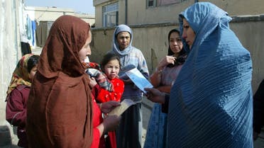 An Afghan health worker (R) speaks to female residents during a house to house campaign against tetanus infection in a village in Kabul.  (F