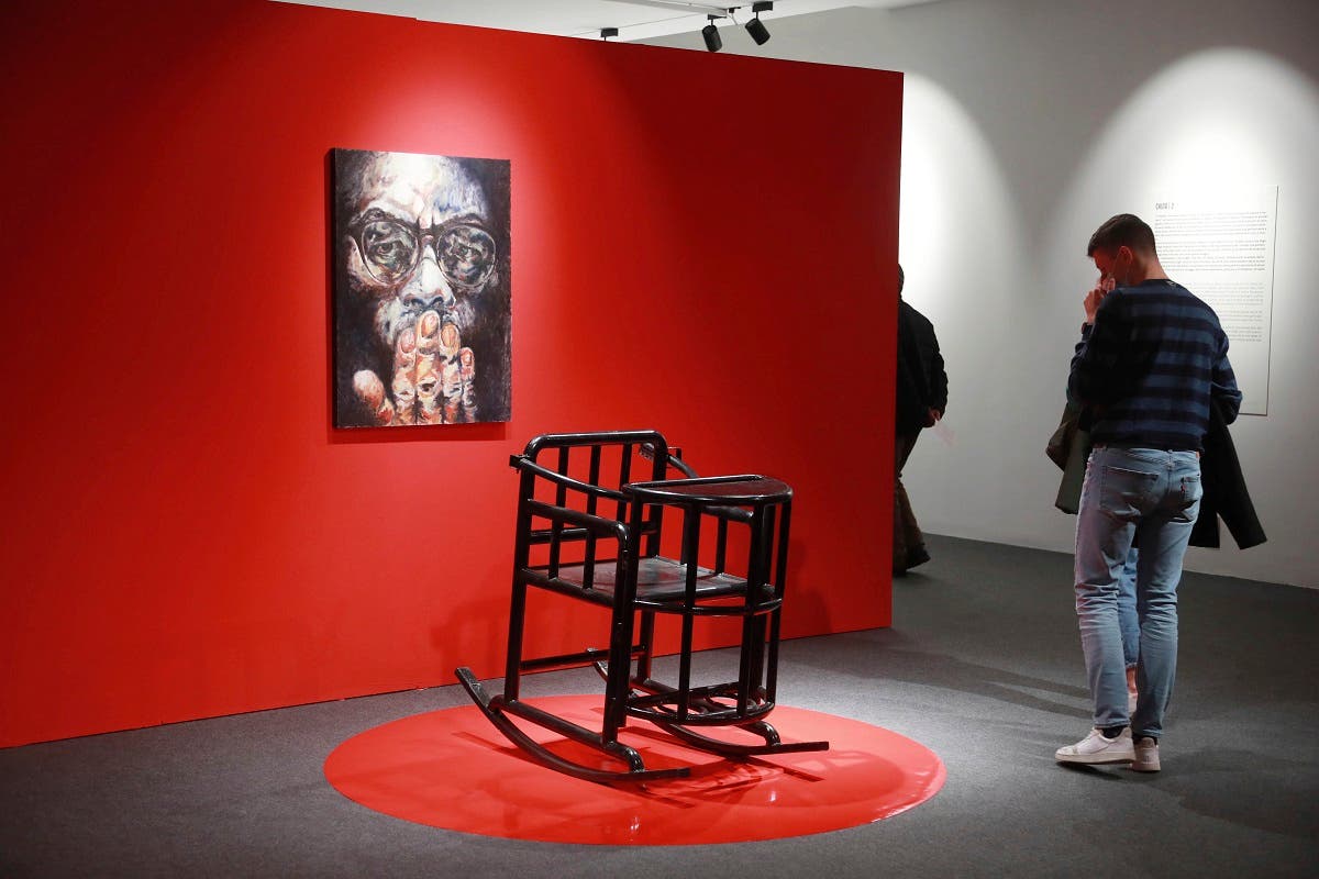 Visitors walk past a torture chair during the opening of artist Badiucao's exhibition in the Santa Giulia Museum, in Brescia, on Nov. 13, 2021. (AP)