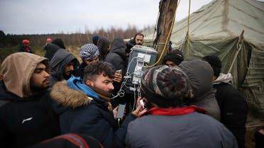 Migrants charge their smartphones as they gather near a tent camp set by Belarusian servicemen and emergency workers at the Belarus-Poland border near Grodno, Belarus, on Nov. 13, 2021. (AP)