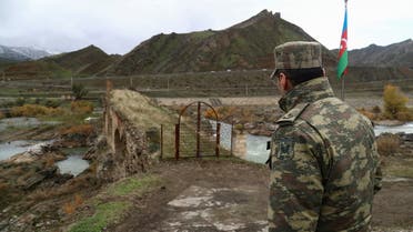 An Azeri service member looks at the ancient Khodaafarin Bridge near the border with Iran in the area, which came under the control of Azerbaijan's troops following a military conflict over Nagorno-Karabakh against ethnic Armenian forces and a further signing of a ceasefire deal, in Jabrayil District, December 7, 2020. Picture taken December 7, 2020. REUTERS/Aziz Karimov