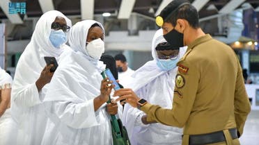 Saudi police member checks pilgrims for vaccination details on their smartphone, after Saudi authorities announced the easing of coronavirus disease (COVID-19) restrictions, at the Grand Mosque in holy city of Mecca, Saudi Arabia, October 17, 2021. (Reuters)