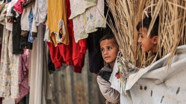 Children look on next to a clothes hanging to dry on a laundry line at the Rafah camp for Palestinian refugees in the southern Gaza Strip on November 16, 2021. (AFP)